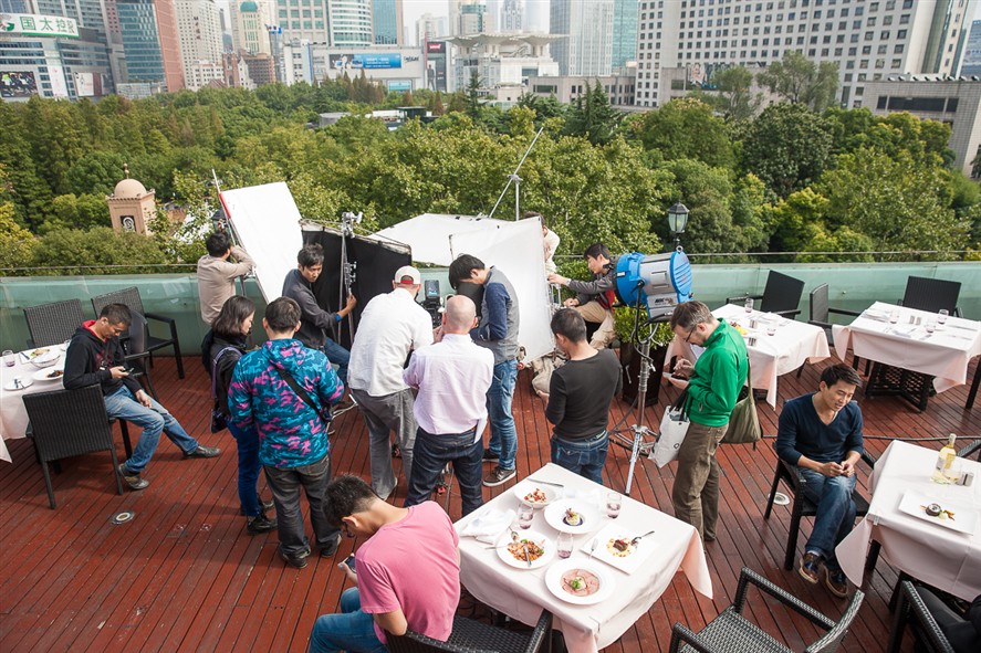Beijing production crew reviewing a shoot on location with city buildings in the background